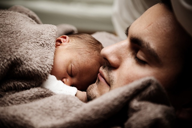 赤ちゃんと一緒に眠る男性
